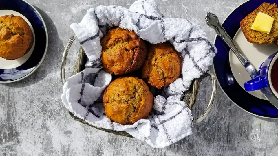 Freshly baked muffins nestled in a striped kitchen towel